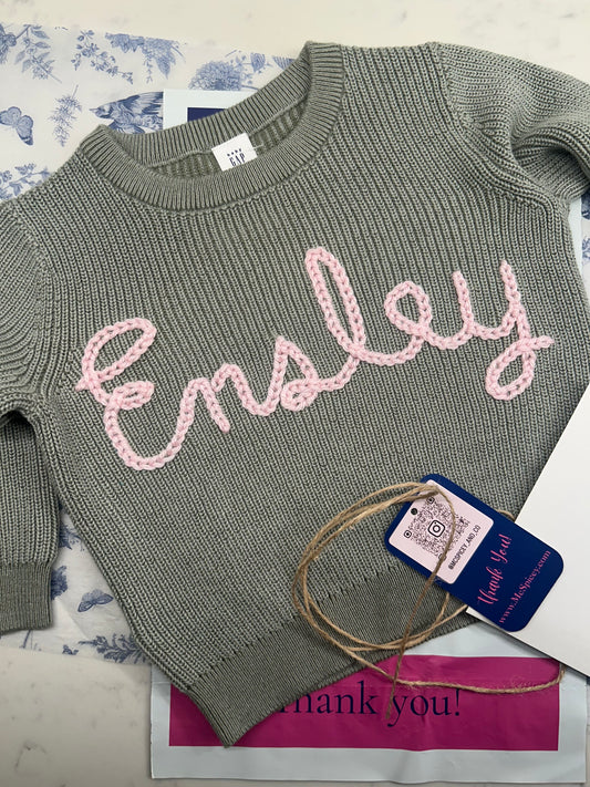 Sage Green Knit Crewneck embroidered with baby name in pink yarn. Personalized baby keepsake gift by McSpicey
