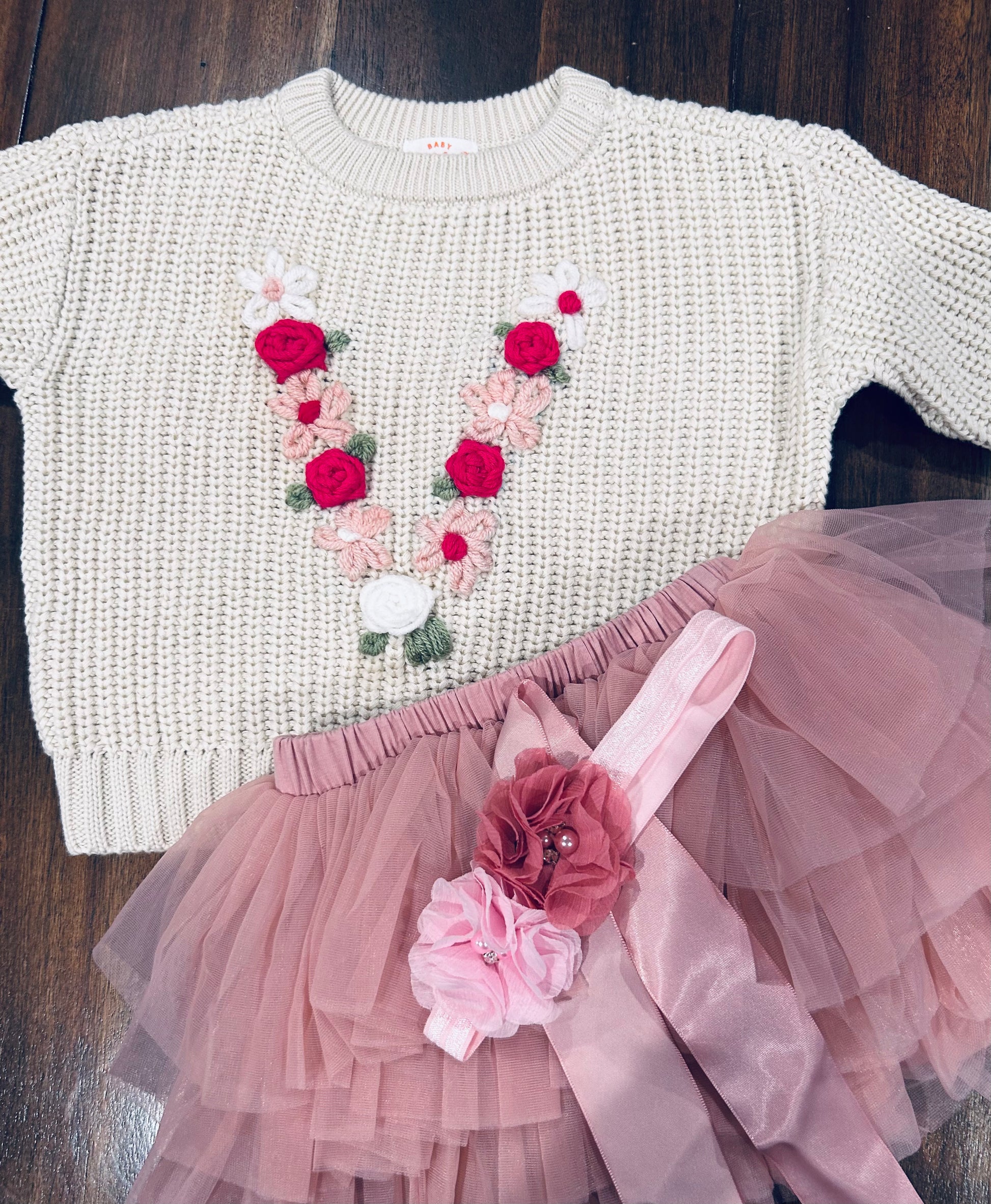 A baby girl's  cream-colored textured knit sweater with a pink and green floral embroidered design. Personalized baby keepsake gift by McSpicey.